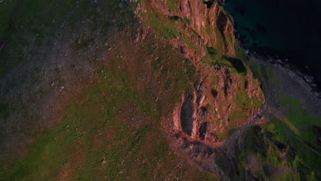 Aerial-Top-down-shot-of-a-steep-mountain-cliff-and-revealing-a-scenic-view-towards-Norwegian-see,-Matinden,-Andoya,-Vesteralen