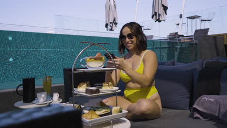 Toma-En-Cámara-Lenta-De-Una-Mujer-En-Bikini-Tomando-Una-Foto-De-Comida-De-Lujo-Junto-A-La-Piscina