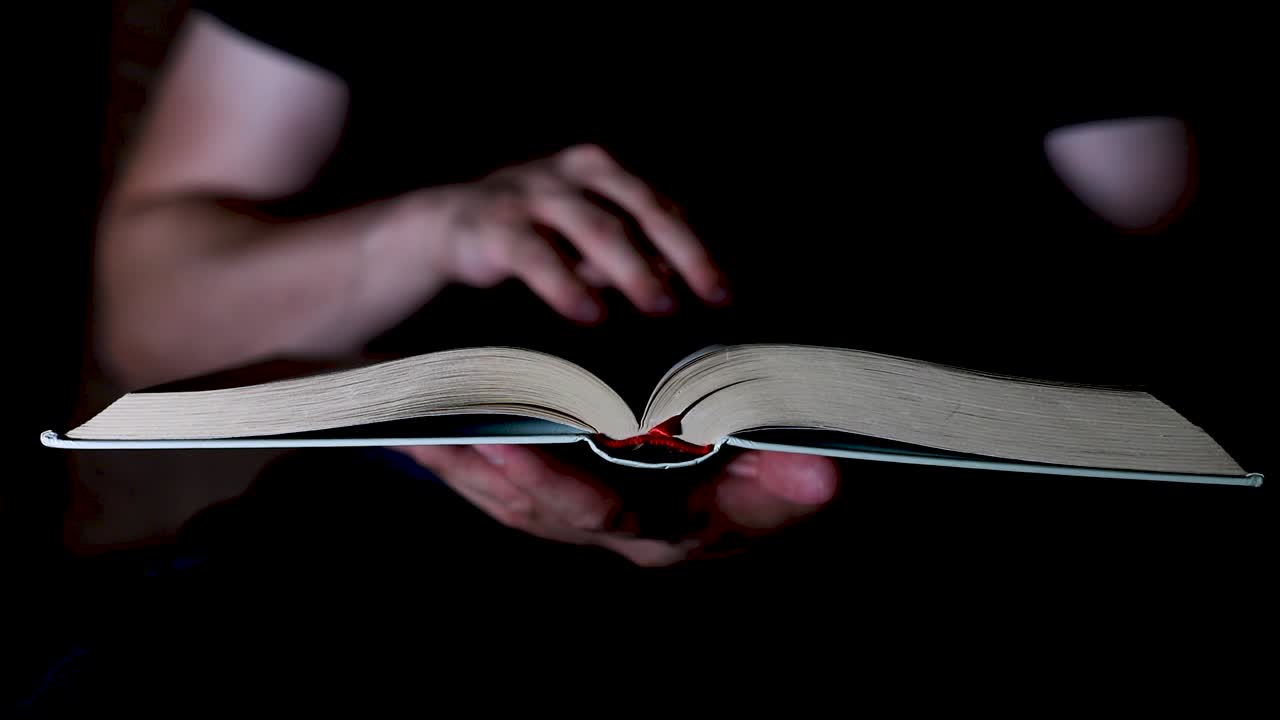 el hombre pasando las paginas del libro en la oscuridad
