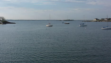 A-low-altitude-drone-shot-over-calm-with-a-few-sailboats-in-the-water