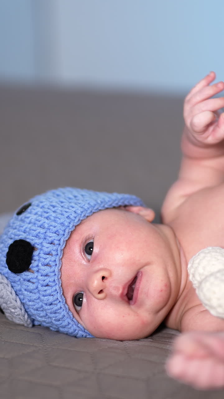 Adorable baby lying on the big bed. Baby in a nice costume of a puppy lies and moves his little feet. Little kid in a funny knitted costume. Vertical video