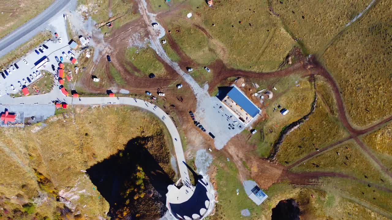 un hermoso monumento contra el fondo de montañas y un lago, un parapente volando, las montañas del cáucaso en georgia cerca de la carretera militar