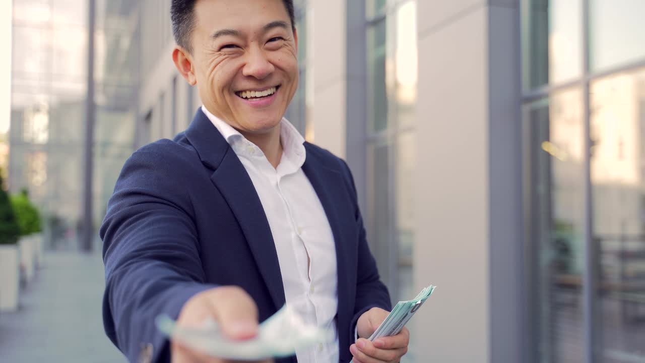 성공한 아시아 사업가, 현금을 계산하고 넘겨주고, 카메라를 바라보며 손을 는다.