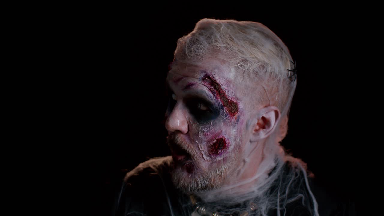 Sinister man Halloween crazy zombie with bloody wounded scars face scared by police lights surrender