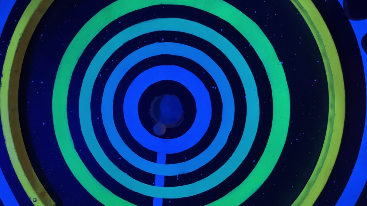 mini golf ball just misses the target hole on a brightly colored dark lane