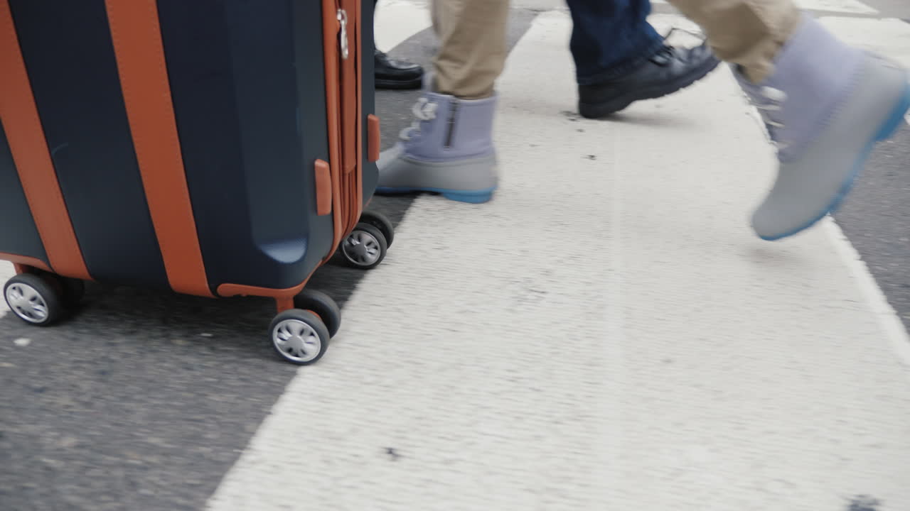 una persona con una bolsa sobre ruedas baja por la concurrida acera de manhattan en nueva york solo las piernas son visibles