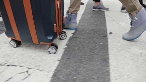 A-Person-With-A-Bag-On-Wheels-Goes-Down-The-Busy-Sidewalk-Of-Manhattan-In-New-York-Only-Legs-Are-Vis