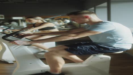 people cycling on exercise bikes in gym