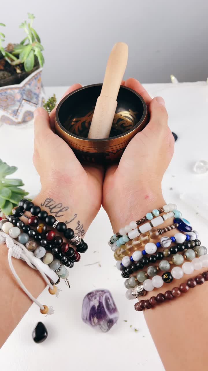 mano sosteniendo un cuenco de canto con pulseras y cristales