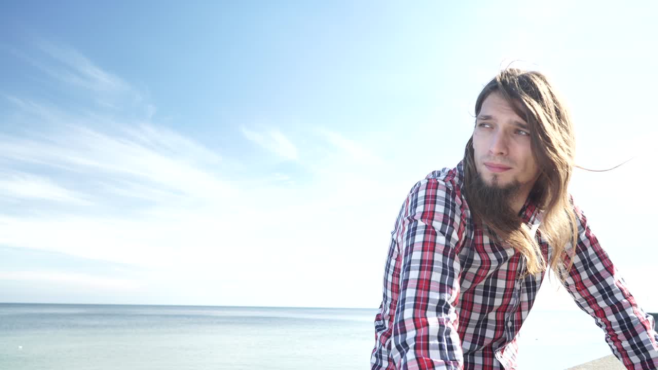 hombre de cabello largo relajándose en la orilla del mar 4k