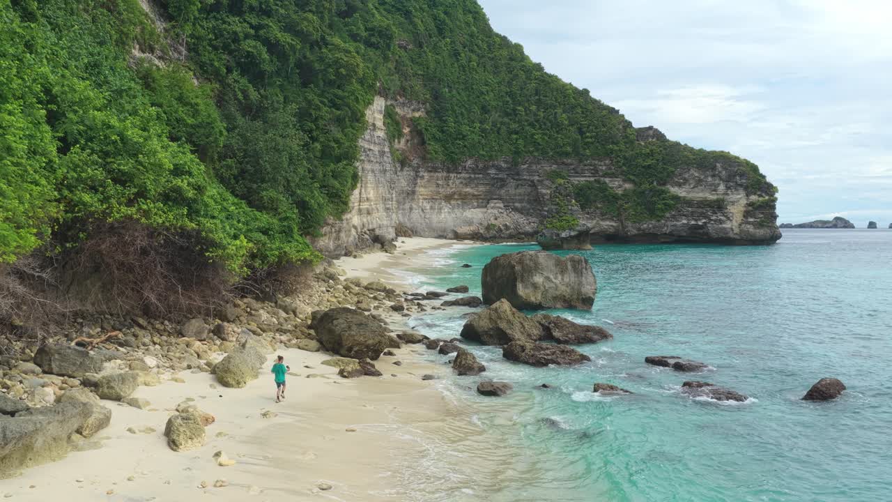 Orang berjalan di pantai tropis terpencil Suwehan di Nusa Penida