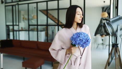 mujer en una bata de baño sosteniendo hortensias en un hogar moderno