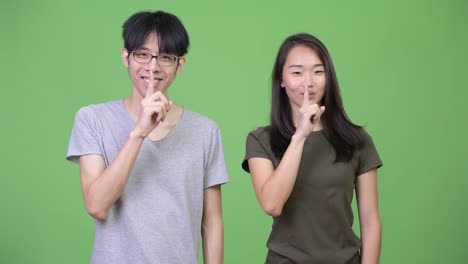 young asian couple with finger on lips together