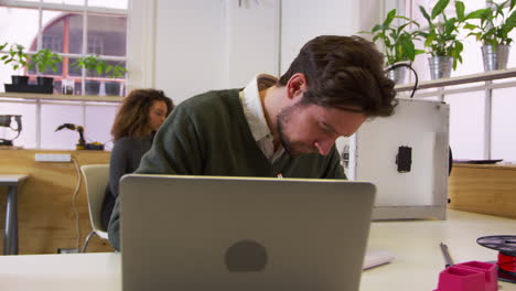 diseñador dibujando en un estudio de impresión 3d y comprobando la computadora, filmado en r3d