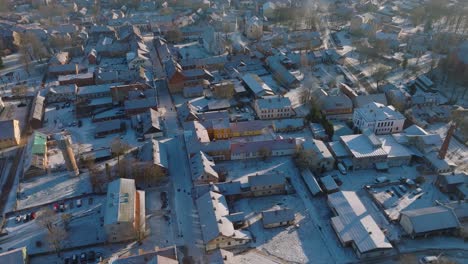 Aerial-establishing-view-of-Kuldiga-Old-Town-,-houses-with-red-roof-tiles,-sunny-winter-day,-travel-destination,-wide-drone-shot-moving-forward,-tilt-down