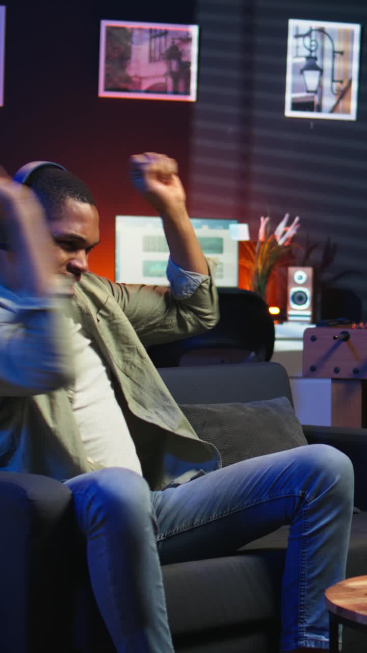 Vertical Video African American guy working on laptop celebrating achievement under neon lights