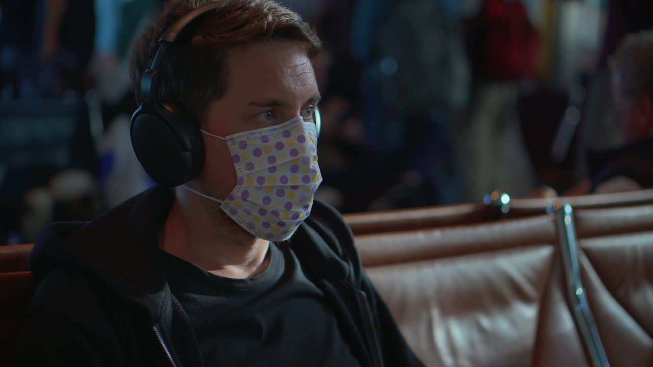 hombre con auriculares y máscara en el aeropuerto