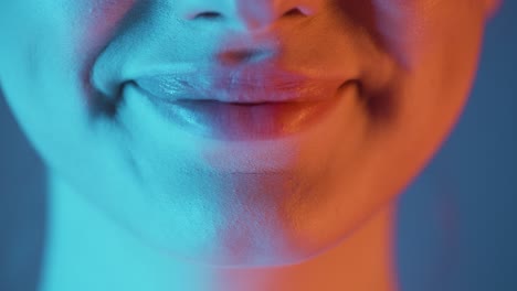 Primer-Plano-Extremo-De-Los-Labios-De-Una-Joven-Hermosa-Mujer-Mientras-Se-Regocija-Simbolizando-Alegría-Y-Satisfacción-Con-Su-Gesto-Con-Contraste-Azul-Naranja-En-Su-Rostro-En-Cámara-Lenta