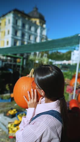mujer sosteniendo una calabaza en el mercado de un granjero