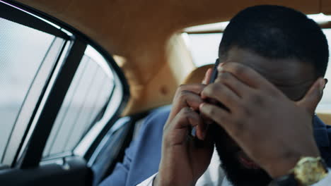 Worried-african-american-man-getting-bad-news-on-mobile-phone-at-modern-car.