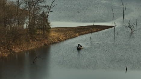 two people fishing from a boat on lake flint creek near lake swepco, arkansas, on an overcast day