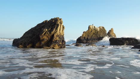 Waves-crashing-in-slow-motion-on-the-shore-of-El-Matador-Beach-at-golden-hour-in-Malibu,-California