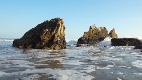 las olas se estrellan en cámara lenta en la orilla de la playa de el matador en la hora dorada en malibú, california.
