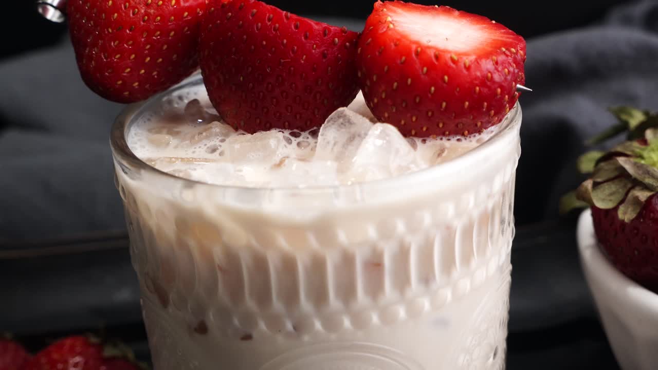 Pink cocktail drink with strawberry liqueur, vanilla vodka and cream. Party drink with strawberries. Fruit cocktail with fresh strawberries as a garnish. Cold and refreshing