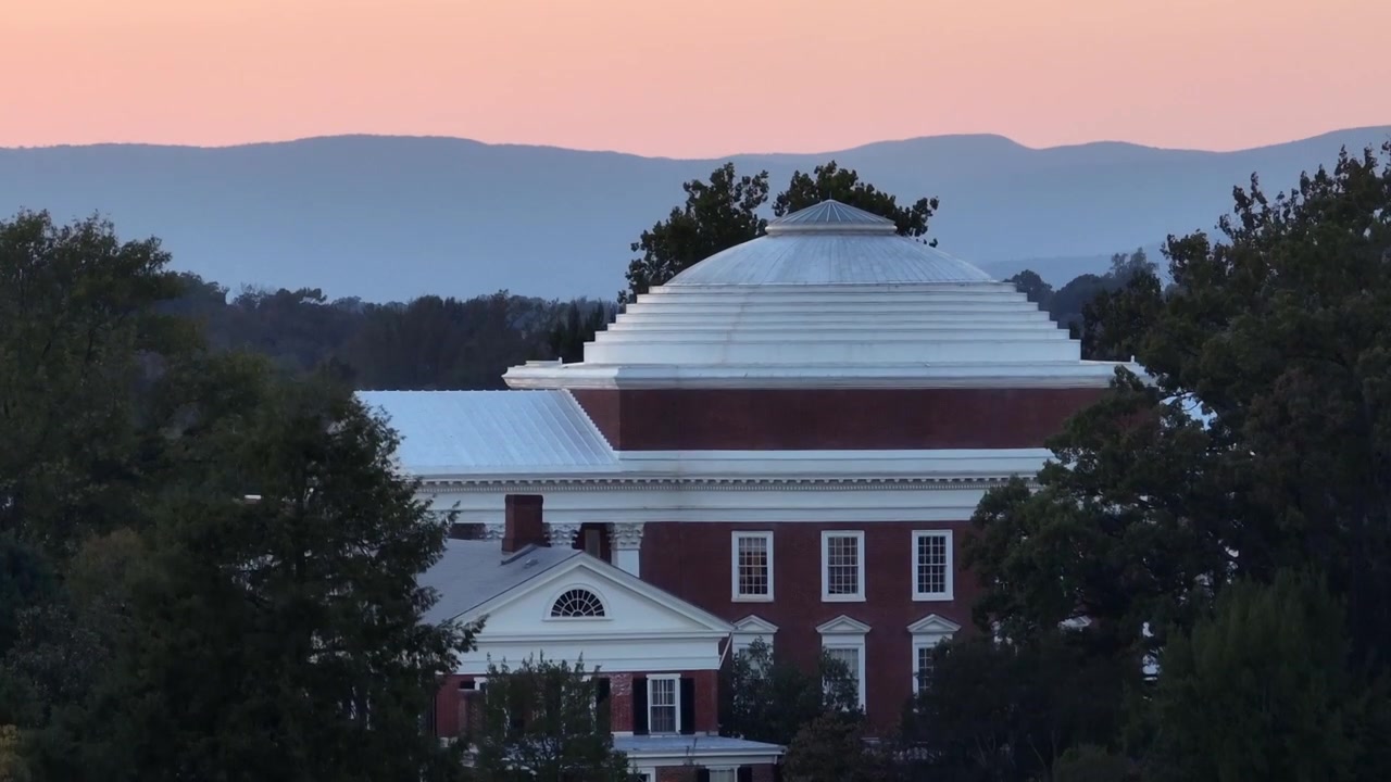 Zoom aereo ascendente dell'edificio La Rotonda all'alba dorata. Università della Virginia nella città di Charlottesville. Paesaggio forestale con montagne sullo sfondo.