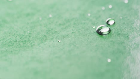 Micro-video-of-close-up-of-water-drops-with-copy-space-on-green-background