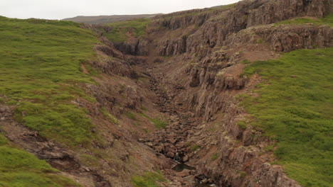 stream flows in canyon in iceland's westfjords, drone shot