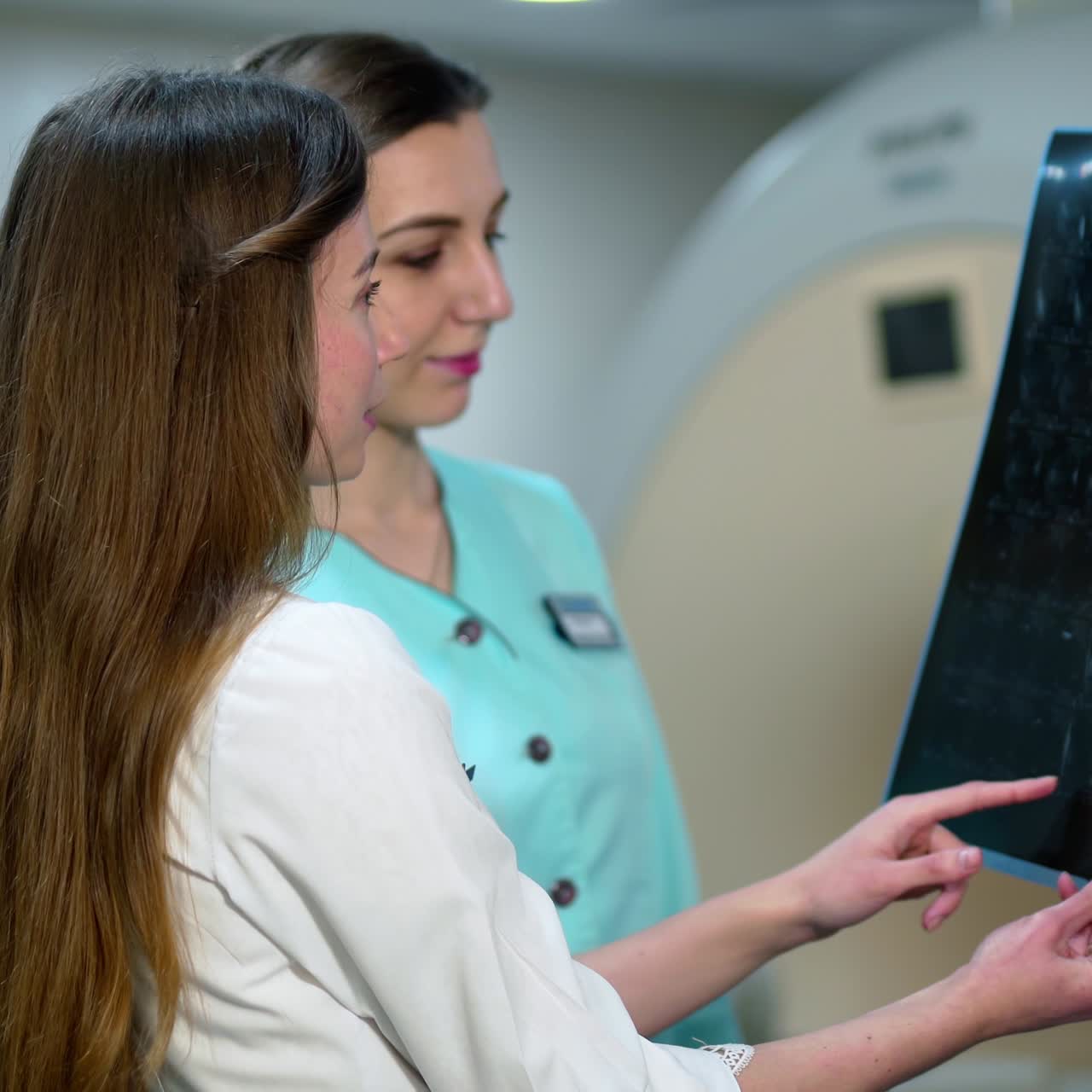 Female doctors examine x-ray in modern clinic. Two women specialists looking at radiographic image and making diagnosis.