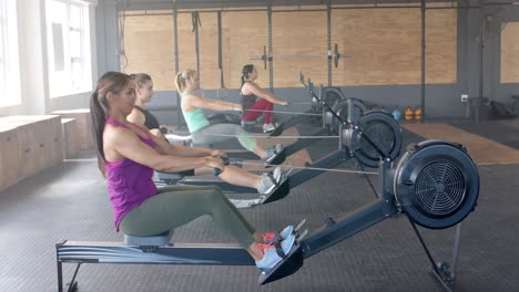 Mujeres-Diversas-Enfocadas-E-Inalteradas-Haciendo-Ejercicio-Con-Máquinas-De-Remo-En-El-Gimnasio,-En-Cámara-Lenta