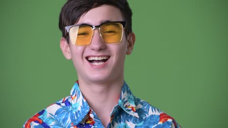 young handsome iranian teenage boy ready for vacation against green background