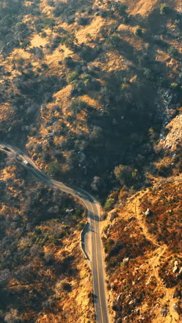 slopes of mountains covered with poor plants. drone footage above the highway in mountains of california. vertical video