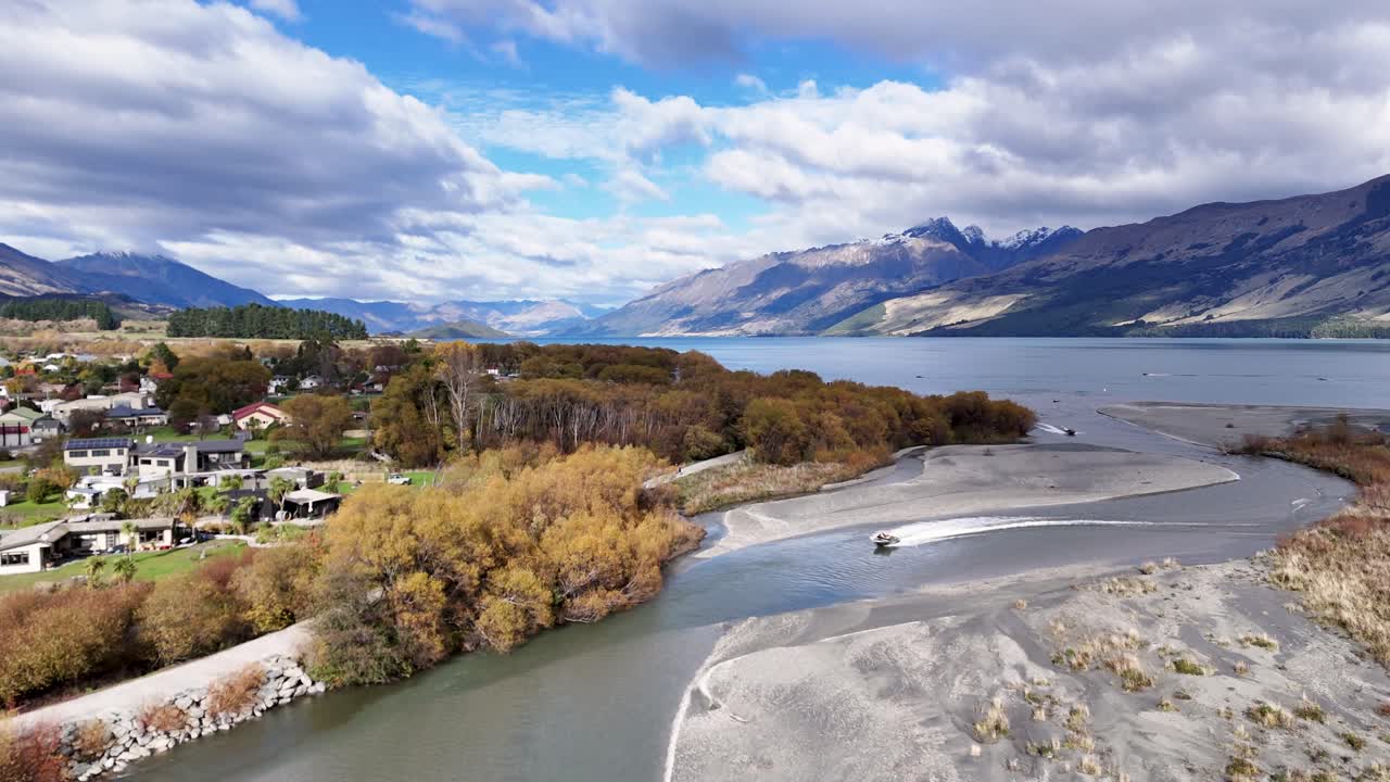 Drone footage captures Glenorchy's river, trees, and mountains under bright skies, showcasing natural beauty and tranquility