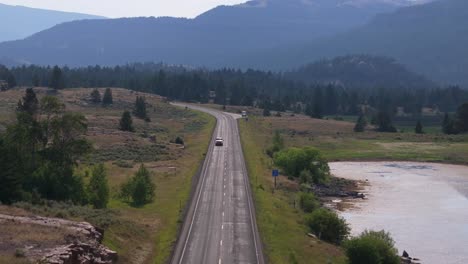 a group of motorcyclists rides down a scenic highway surrounded by mountains and greenery