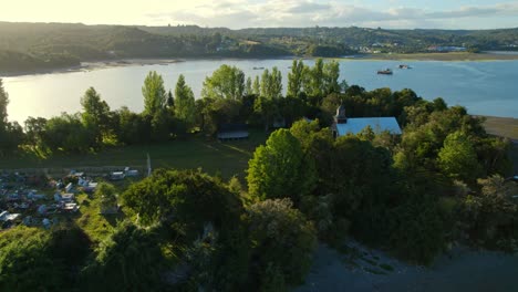 Aerial-orbit-over-aucar-island-and-its-cemetery-with-church,-chiloe,-Chile,-island-of-the-sailing-souls