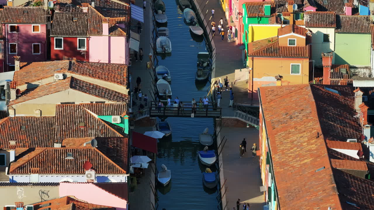 Aerial drone view of boats on the sides of a canal near the colourful houses of Burano, Italy