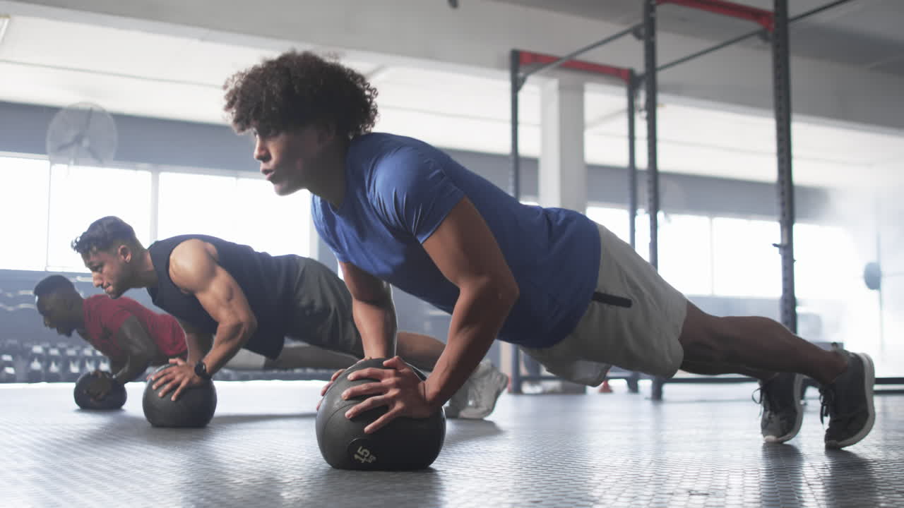 Men doing push-ups on medicine balls during intense gym workout session