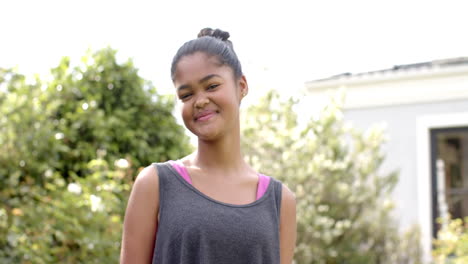 portrait of happy african american girl smiling in sunny garden, copy space, slow motion