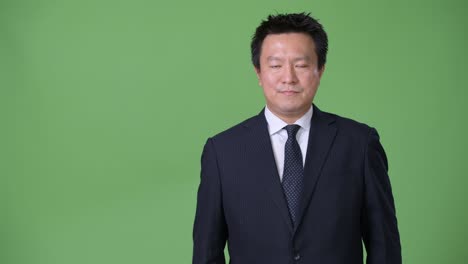 mature japanese businessman against green background