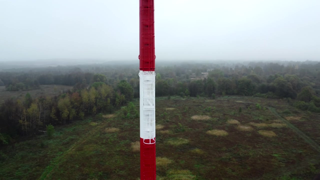 Luftfoto af rødt og hvidt kommunikationstårn i tåget landskab