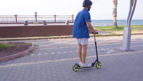 un joven monta un scooter en la playa.