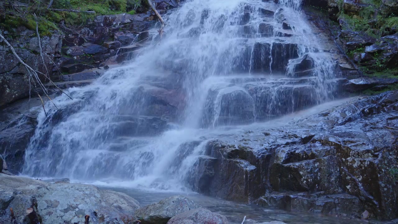Vakkert fossefall som kaskader over naturlige fjellformasjoner i et rolig, frodig skogsmiljø, perfekt for natur-, reise- eller avslapningsprosjekter.