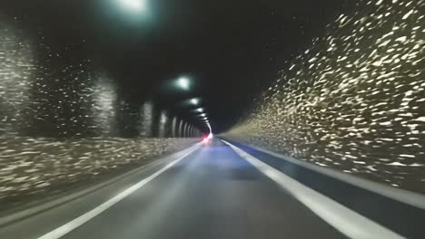 la nieve cae suavemente mientras un coche conduce a través de un túnel oscuro por la noche, creando una atmósfera de invierno serena