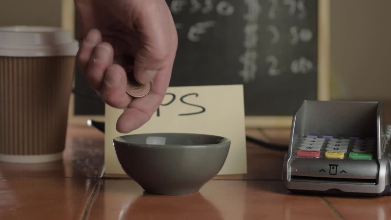 Hands putting coins in tip jar in cafe close up shot