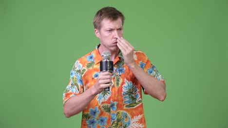 young handsome tourist man talking on microphone and forgetting something