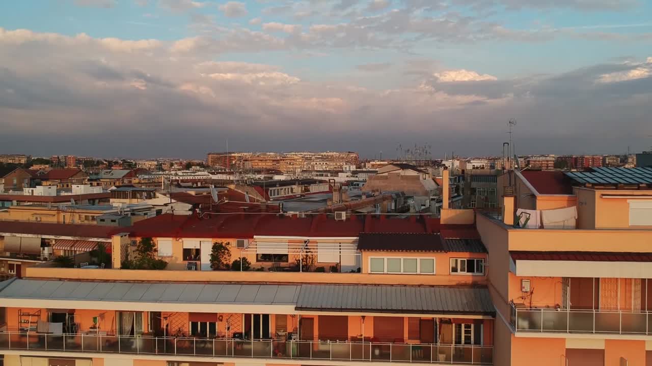 Long cityscape appearing behind a big apartment block, rising drone