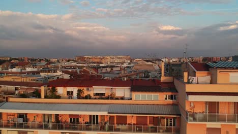 long cityscape appearing behind a big apartment block, rising drone